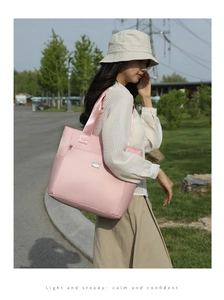 Detail of pink fabric tote bag with front zipper pocket and metallic logo plaque