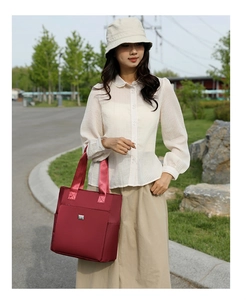 Detail of burgundy waterproof nylon tote bag with side pocket and sturdy fabric handles