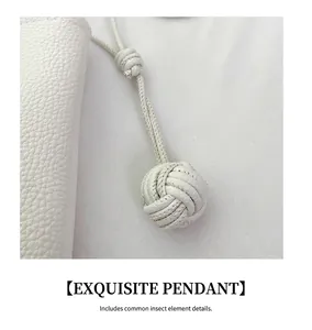 Macro detail of a white pebbled leather woven ball pendant on a designer bucket bag