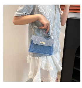 Detail of blue transparent PVC crossbody bag featuring quilted texture and golden metal lock