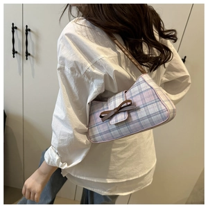 Détail du sac baguette à carreaux rose et bleu avec nœud en cuir marron et bandoulière