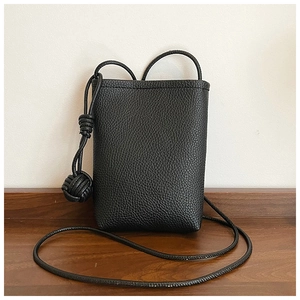 Detailed view of black litchi grain leather phone bag with decorative woven knot detail