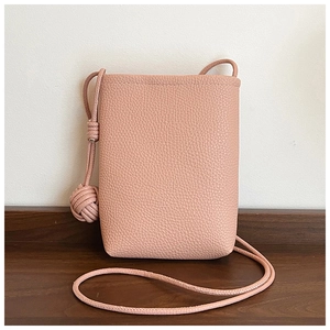 Detailed macro view of the grainy lychee leather texture on a pink small crossbody phone bag