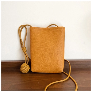 Close-up of ginger yellow leather mini crossbody bag with textured pebble grain finish
