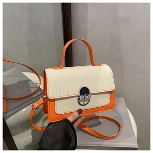 Detail of color-block crossbody bag with orange leather and horseshoe metal clasp lock