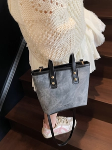 Sac cabas gris en denim avec poignées en cuir noir et détails de rivets dorés