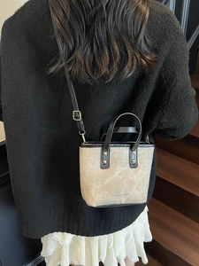 Sac à main tendance en toile bicolore avec lanières en cuir noir porté par un mannequin