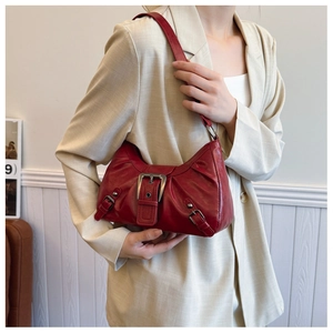Detail of vintage burgundy shoulder bag with distressed metal buckles and pleated leather texture