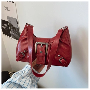 Close-up of a glossy red underarm bag with a vintage metal buckle and rivet details