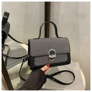 Macro detail of the grey twill texture and silver oval metal buckle on the shoulder bag