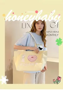 Detail of a large cream canvas tote bag featuring a pink plush heart embroidery patch