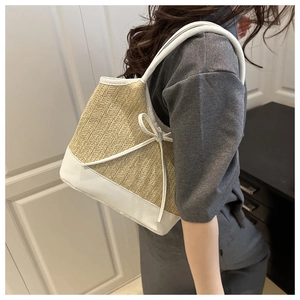 Close-up of woven straw tote bag with white leather trim and side bow detail