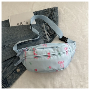 Detalle del bolso de cintura azul claro con motivos de rosas y tiradores tejidos
