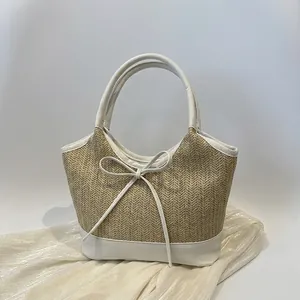 Detail der gewebten Stroh-Tasche mit weißem Lederbesatz und dekorativer Schleife