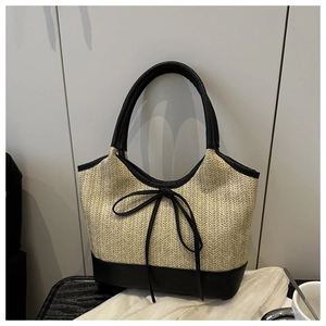 Detail der handgewebten Strohtasche mit schwarzen Lederakzenten und Schleifendesign