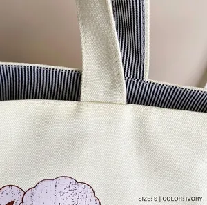 Detail of canvas tote handle with striped lining and durable reinforced stitching