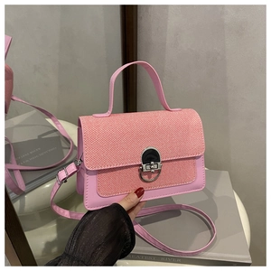 Detail of pink crossbody bag featuring a textured flap, metallic lock, and leather strap