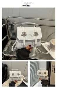 Detail view of white leather square bag with star metal accents and brand lettering