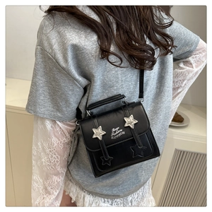 Detail of black crossbody box bag featuring silver metallic stars and printed lettering