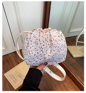 Detailed view of floral canvas bucket bag with drawstring closure and thin white strap