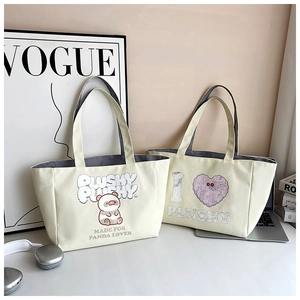 Close-up of canvas tote bags featuring cute panda graphics and heart art lettering