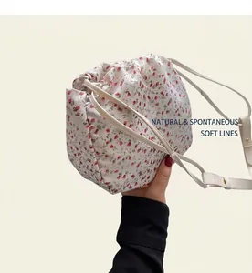 Detailed view of floral drawstring handbag with red flower print and leather shoulder strap