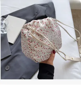 Detailed view of floral drawstring handbag with red flower print and leather shoulder strap