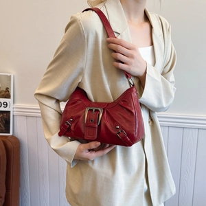 Retro red faux leather shoulder bag with vintage buckle detail worn by a model in a beige suit