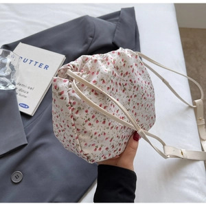 Macro detail of floral bucket bag featuring drawstring closure and textured fabric