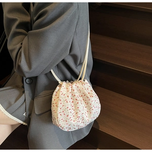 Close-up of small floral canvas crossbody bag with drawstring closure on model
