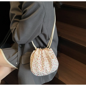 Detail of floral drawstring bucket bag with red flower patterns on a creamy base