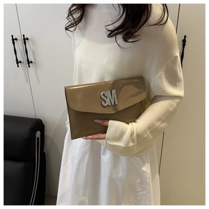 Detail of tan patent leather envelope bag with sparkling rhinestone SM logo detail