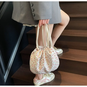 Détail du sac à cordon floral avec motifs de fleurs rouges et texture en toile