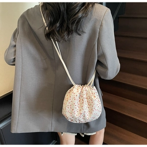 Detail of floral canvas bucket bag with drawstring closure on model in a blazer