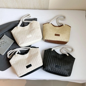 Detalle de bolsos tote de paja trenzada con asas de cuerda de algodón y parches de cuero