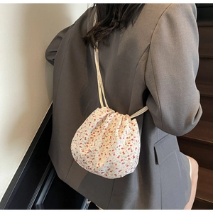 Detailed view of mini floral canvas drawstring bag with shoulder strap worn on crossbody