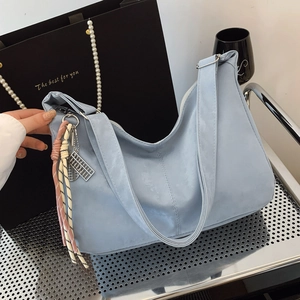 Detail of light blue suede tote bag featuring braided tassel and silver abacus pendant