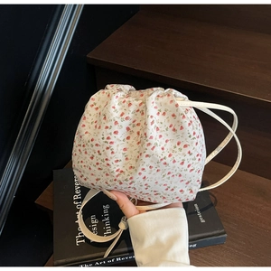 Detailed view of floral canvas bucket bag with drawstring closure on a wooden surface