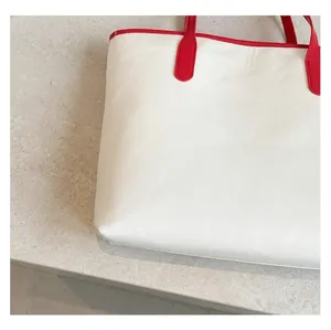 Detail of red and white tote bag showing durable waterproof fabric and sturdy handles