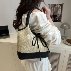 Stroh-Stofftasche mit schwarzer Lederschleife und runden Griffen über der Schulter