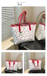 Macro detail of red cherry prints on a white tote bag with red leather strap handles