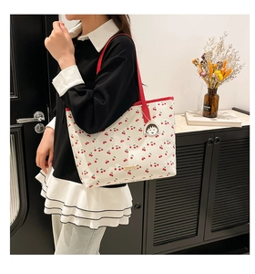 Detail of cherry print tote bag featuring a cute character metal charm on the handle