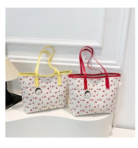 Detailed view of cherry print tote bags with colored handles and cartoon charms