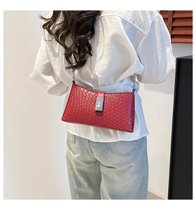 Model wearing a red woven textured crossbody bag with silver chain strap on white shirt