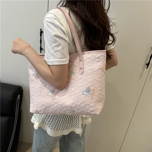 Pink quilted tote bag with colorful butterfly embroidery shown on model shoulder