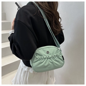 Dettaglio della borsa a tracolla verde menta a pieghe con logo circolare in metallo