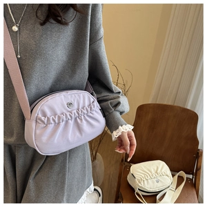 Detail of lavender nylon crossbody bag with adjustable strap and pleated design