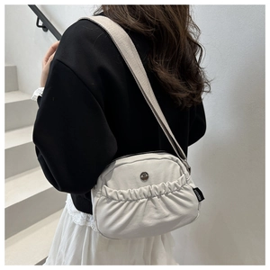 Detail view of the white pleated canvas backpack with a wide beige woven shoulder strap