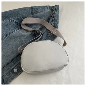 Detail of grey pleated shoulder bag with adjustable strap on a denim background