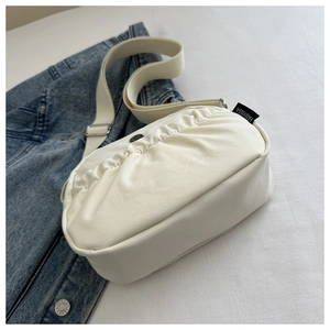 Detailed close-up of white pleated canvas shoulder bag with branded FANYISSA side tag